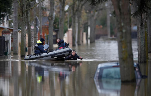 Sông Seine tràn bờ, người Pháp chèo xuồng vượt lụt giữa Paris